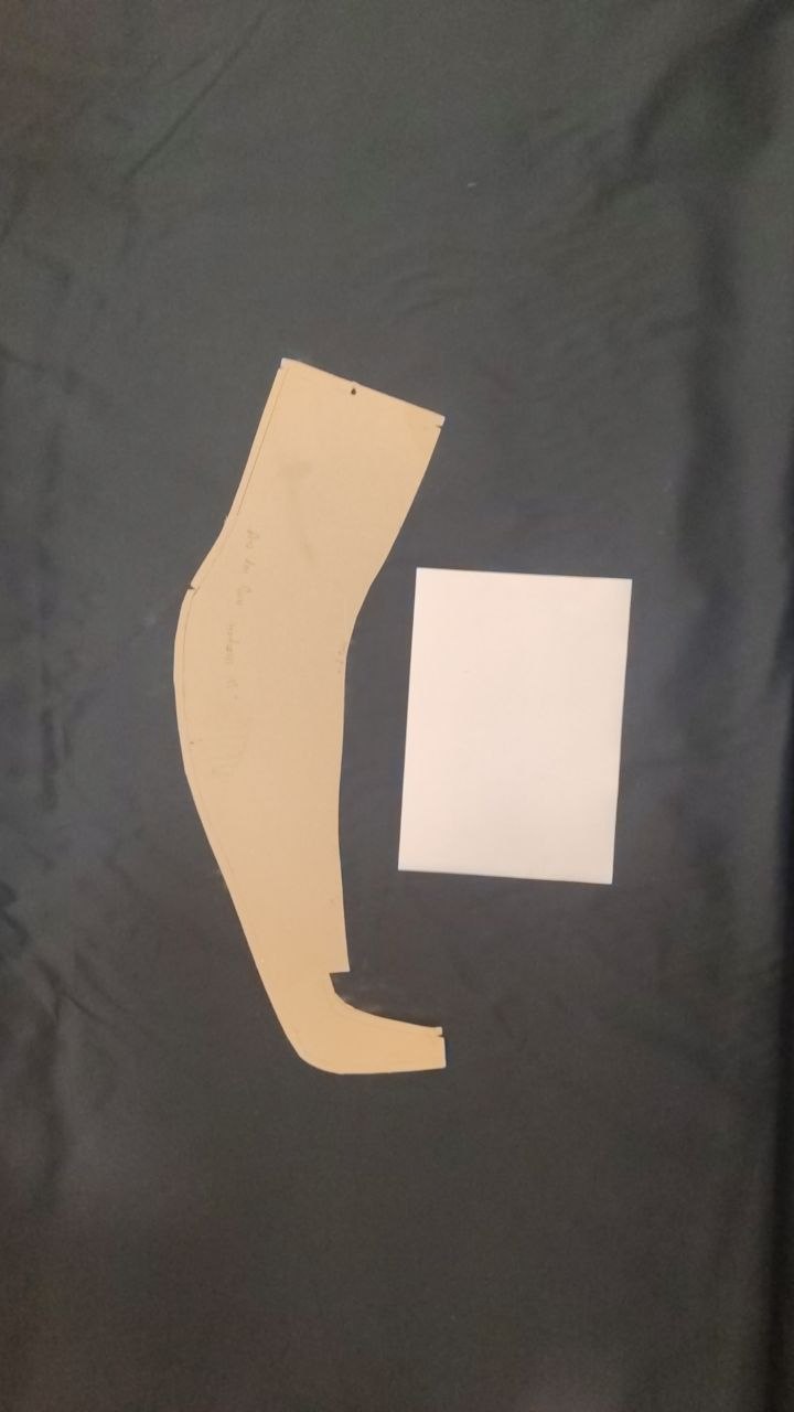 A paper sewing pattern photographed from above with a sheet of paper beside it for scale